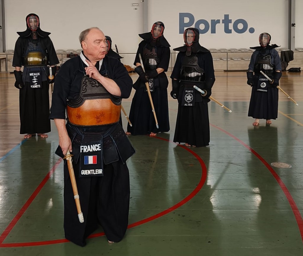 Imagem mostra Michel Guentleur Sensei a lecionar e grupo de 4 kenshi a ouvir as explicações. 
